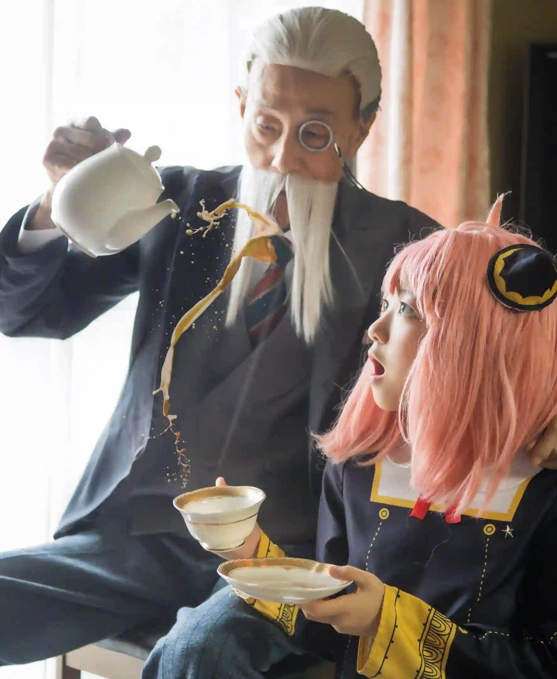 Avô e neta vestidos como Henry Henderson e Anya do anime SPY x FAMILY, deitados no chão em pose de cosplay